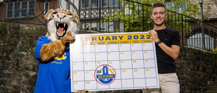 Bruiser Bobcat and student holding February calendar