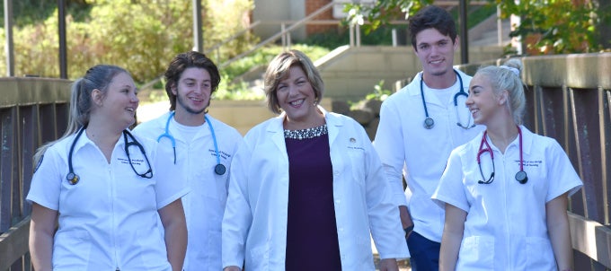 Five nurses walking on campus