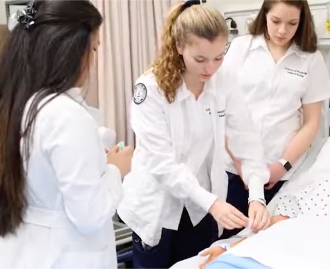 Three nurses working with patient