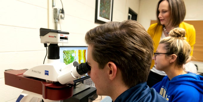 Two Biochemistry majors at microscope with professor