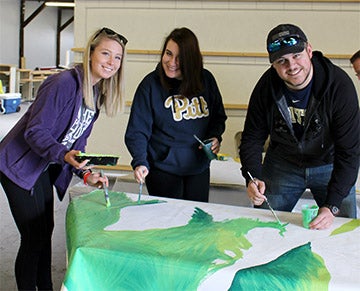 Three students working on mural