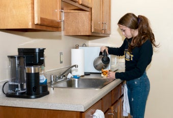 Student pouring drink over sink in Westmoreland Hall kitchen