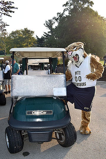 Pitt-Greensburg's mascot, Bruiser, the bobcat, standing next to a golf cart