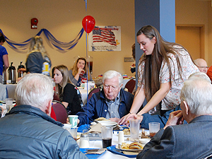 Student serving a veteran at the annual luncheon
