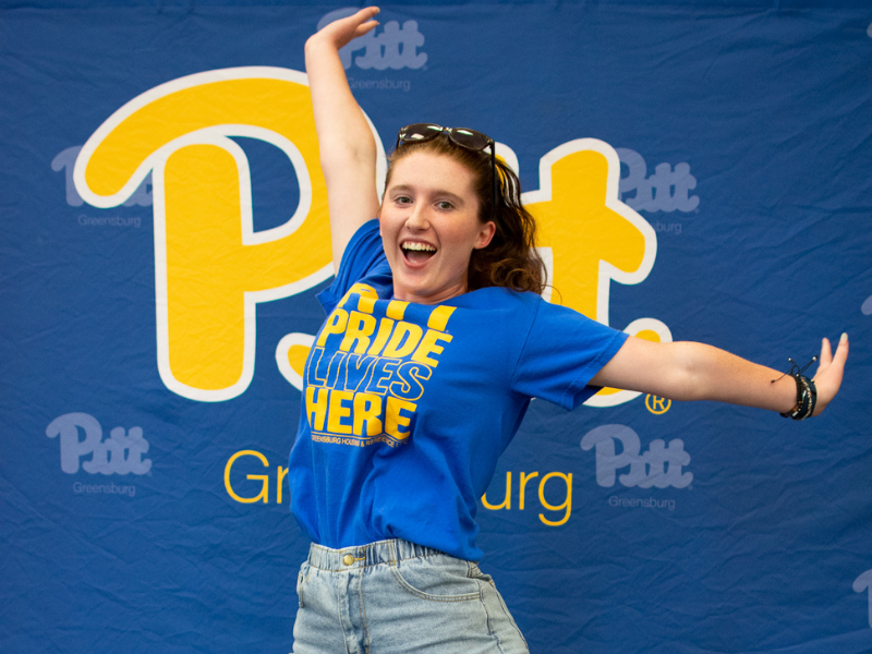 Student jumping in front of Pitt sign
