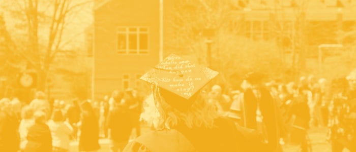 Student with graduation cap facing Millstein Library