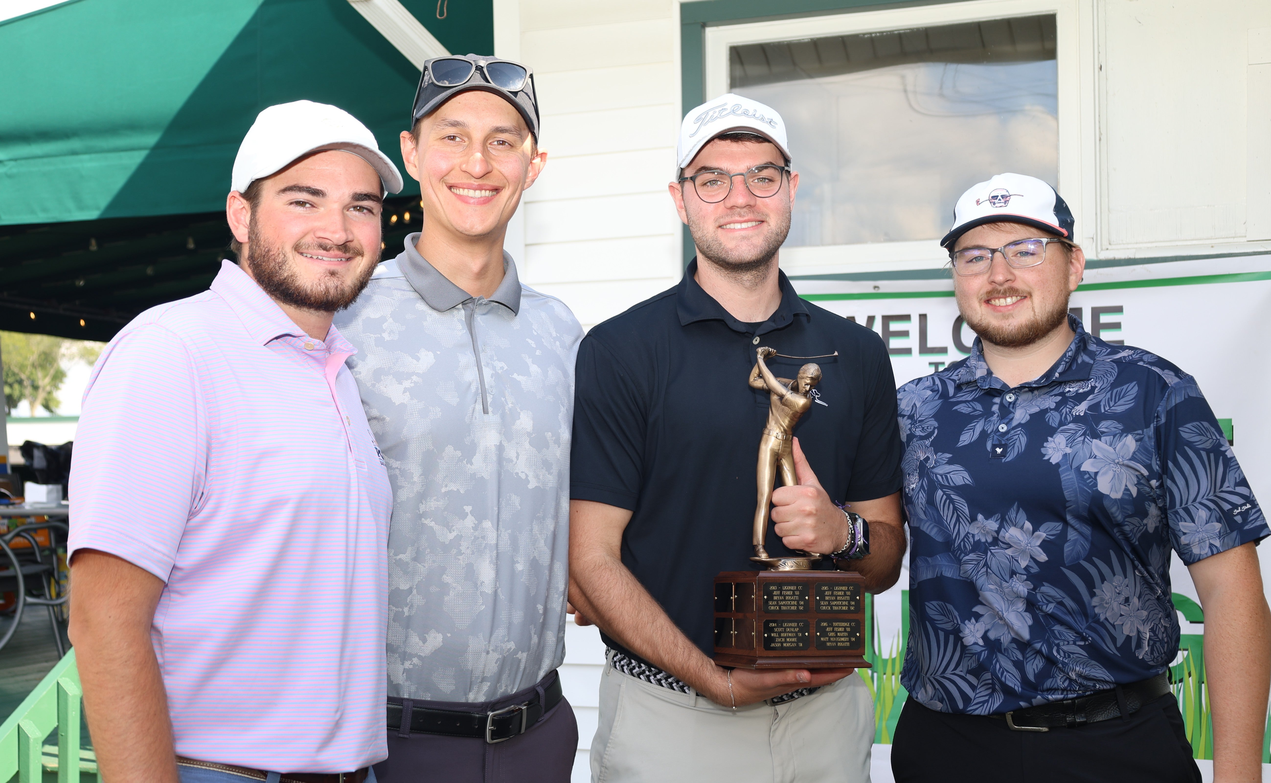 Four people posed with Golf Outing trophy.