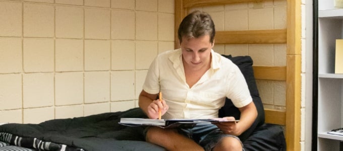 Student sitting on bed with book