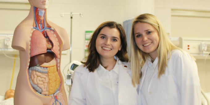 Two students smiling posed near anatomical cross-section