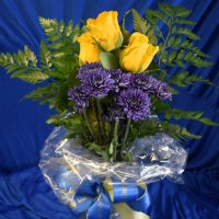 Three (3) yellow roses and blue flowers with greens, wrapped in cellophane, and tied with a ribbon. $19.50 each