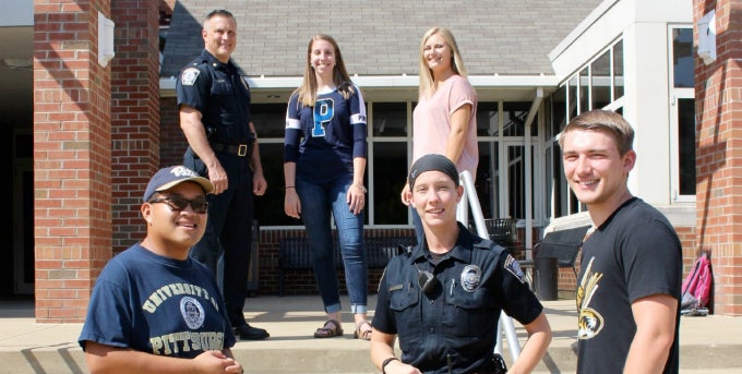 Two campus police officers with four students posing on Chambers Hall steps