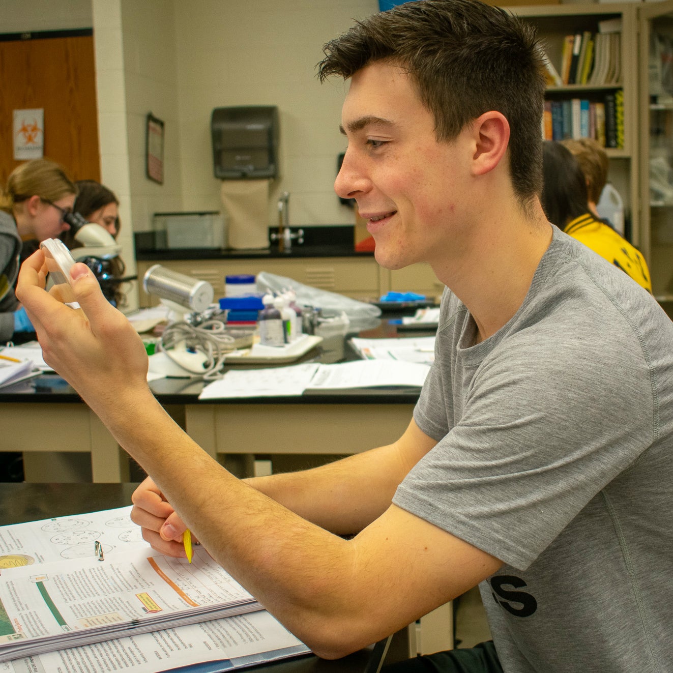 Student examining petri dish.