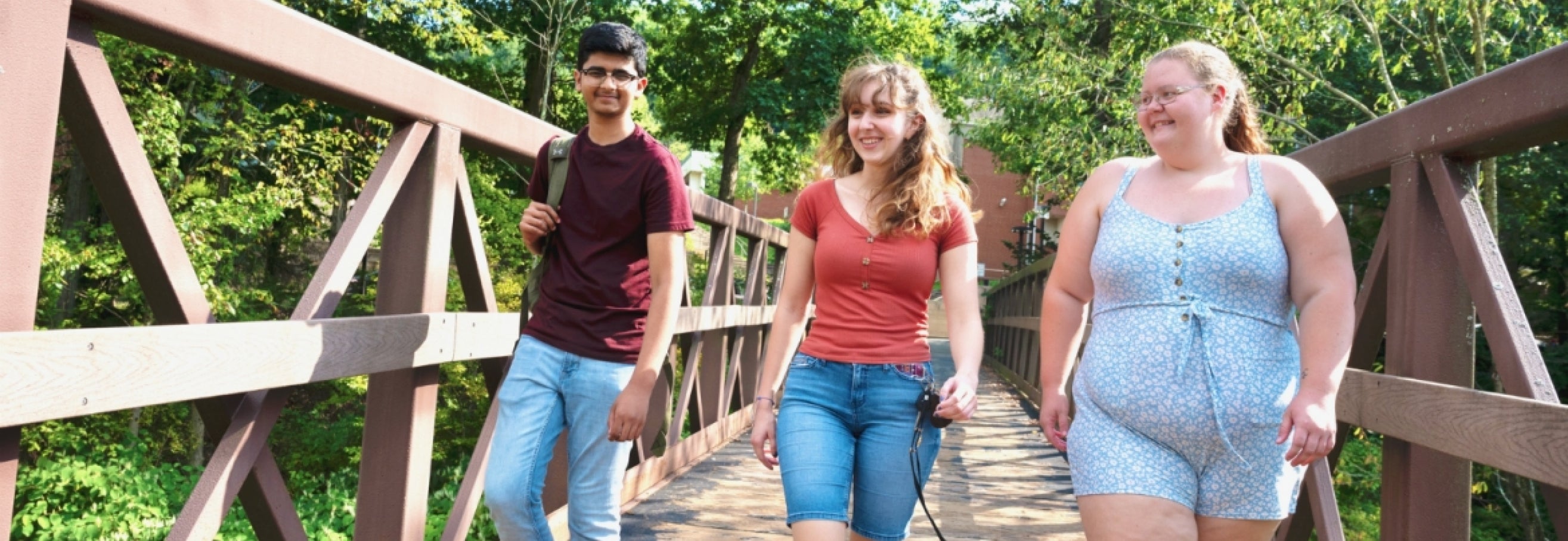 Three students walking across campus footbridge