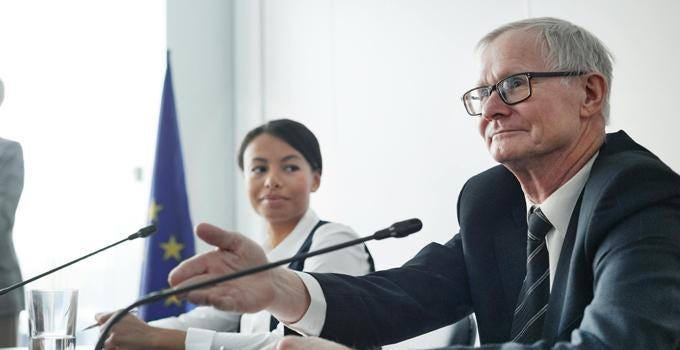 people speaking in microphones at a desk