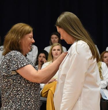 A student nurse receives her pin from a family member