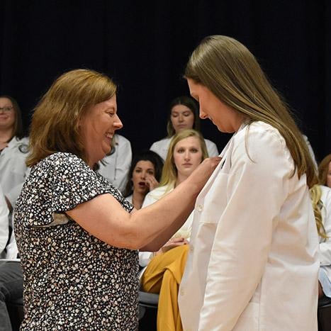 A student nurse receives her pin from a family member