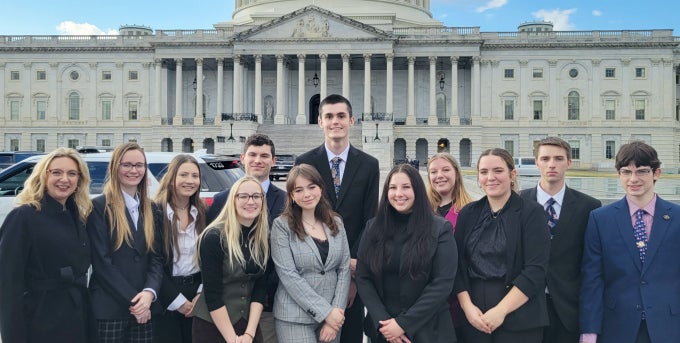 Group of students and instructor dressed formally outside U.S. Capitol building